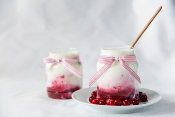 natural yogurt with cranberry jam in a jar on a white