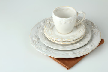 cups, plates and saucers on the cloth on a white isolated background