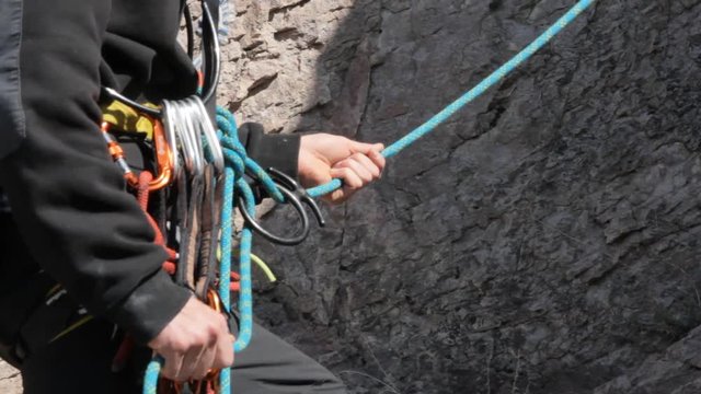 Close-up detail of rock climber wearing safety harness and climbing equipment outdoor
