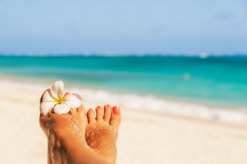 Holiday concept. Woman feet with frangipani flower, relaxing on