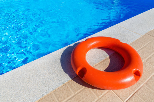 Orange life buoy lying at swimming pool