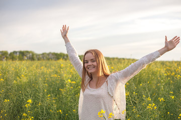 Naklejka na ściany i meble woman with open arms in the green rapseed field at the morning