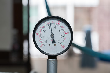 Industrial pressure meter - barometer and water pipes in the background
