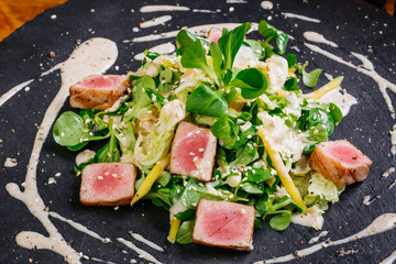 Seared tuna coated sesame seeds with green salad on plate