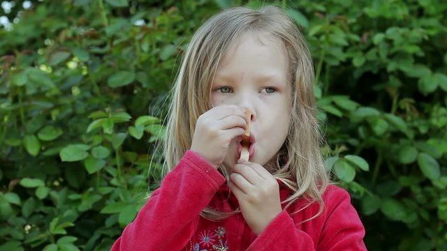 Little cute girl playing with a stick from a popsicle and looking at the camera.