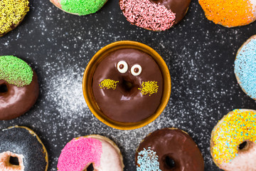 Assorted donuts with coffee and powder flour on black background