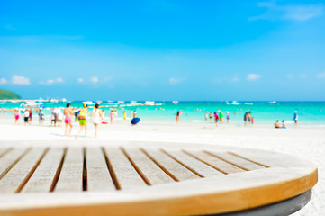 Round table top on blur beach background with people in colorful clothes