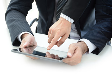 Two businessmen using tablet computer with one hand touching screen