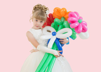 little girl with balloons in a ball gown isolated on a pink background
