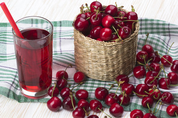 Cherry basket and juice on wooden background