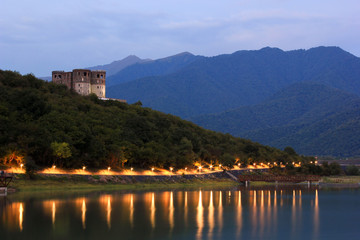 Fototapeta na wymiar mountain lake at sunset with castle on hill