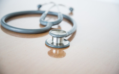 Close up view of grey stethoscope on brown background.