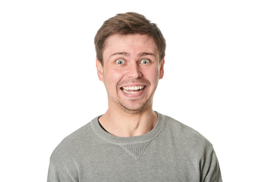Happy young man with manic expression, on gray background