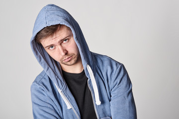 Fototapeta na wymiar Handsome young man with light beard in blue hoodie, on gray background