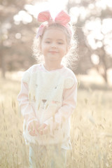 Smiling baby girl 4-5 year old wearing stylish sweater outdoors. Looking at camera. Childhood. Summer time.