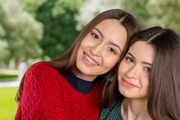 Obraz premium Two beautiful sisters hugging each other and smiling