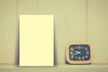 Mock up black paper, Yellow alarm clock against dirty wooden wal