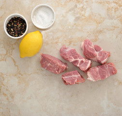 Sliced raw pork meat and salt and pepper on a marble background