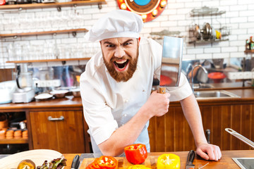 Angry bearded chef cook holding meat cleaver knife and shouting