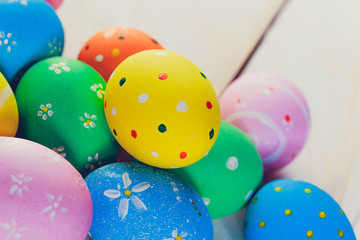 Easter eggs painted in pastel colors on white wooden background.