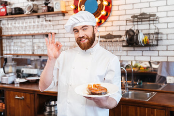 Chef holding salmon steak on plate and showing ok gesture