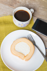 Vanilla roll cake and coffee cup with smartphone, in morning time
