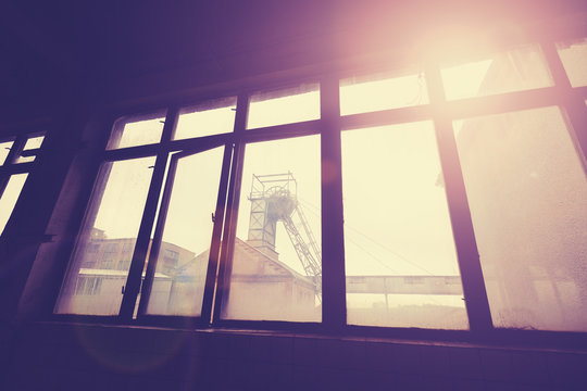 Vintage toned coal mine pithead seen through windows, lens flare effect.