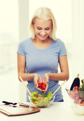 Obraz na płótnie Canvas smiling woman cooking vegetable salad at home
