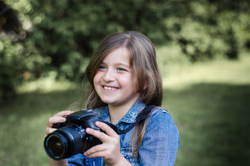 Happy beautiful little girl with photocamera, summer portrait.