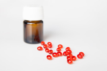 Pile of red pills on white table. Bottle