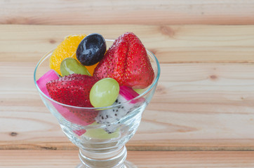 mixed fruit in glass on wood table, healthy food
