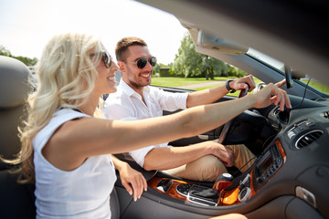 happy couple using gps navigator in cabriolet car