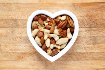 Raw organic nuts in heart shaped bowl