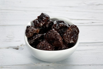 Getrocknete Pflaumen in weißer Schüssel auf weißem verwittert