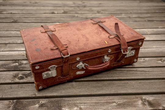 Brown vintage leather suitcase on a wooden deck lying flat viewed high angle in a travel concept