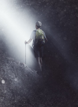 Mountaineer walking towards a beam of light