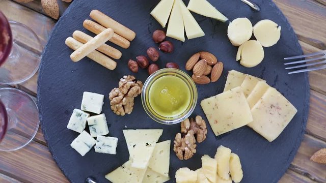 Top view cheese plate Assortment of various types of cheese on dark slate cutting board rotation 360