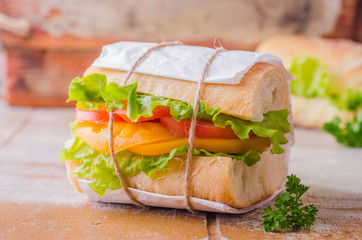 Sandwich with leaves salad and tomatoes on wooden baskgraund. Selective focus