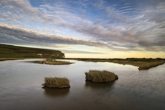 Landscape image of tidal pool at coast during evening with drama