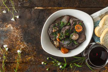 Beef bourguignon in a ceramic dish on the old metal and flowers
