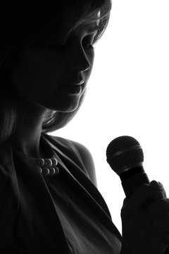 silhouette of a woman singing with a microphone in hands