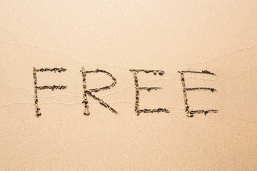 Free word handwritten in sand on sunny beach