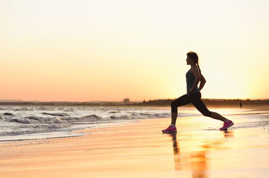 Woman exercising on beach at sunset