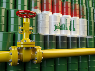 Oil pipe line valve in front of the flag of Iraq on the oil barr