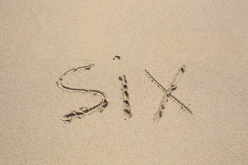 Six number written on sand. Summer beach background