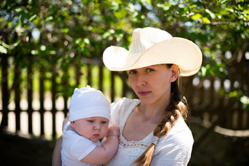 Mom in a cowboy hat holding his young son on the nature