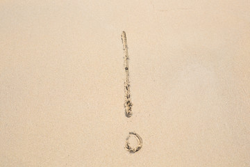 Fototapeta na wymiar Exclamation mark symbol written on sand. Summer beach background