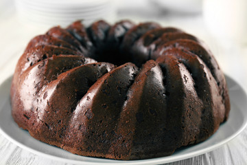Chocolate cake on plate on white wooden background
