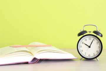 clock near open book on green background