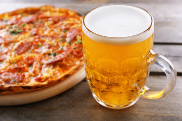 Tasty pizza and glass of beer are on wooden table, close up